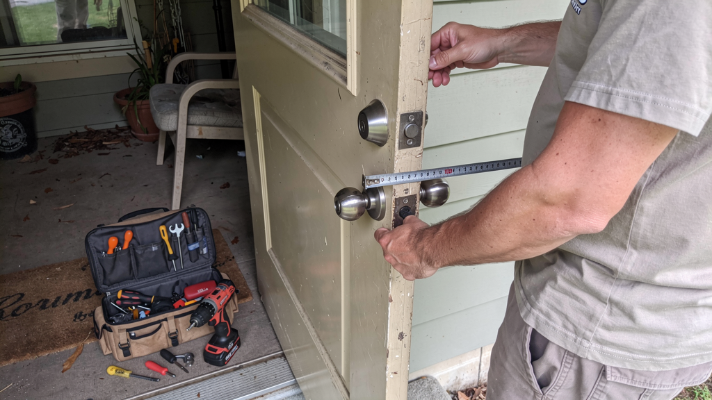 Residential door hardware and a locksmith measuring a deadbolt